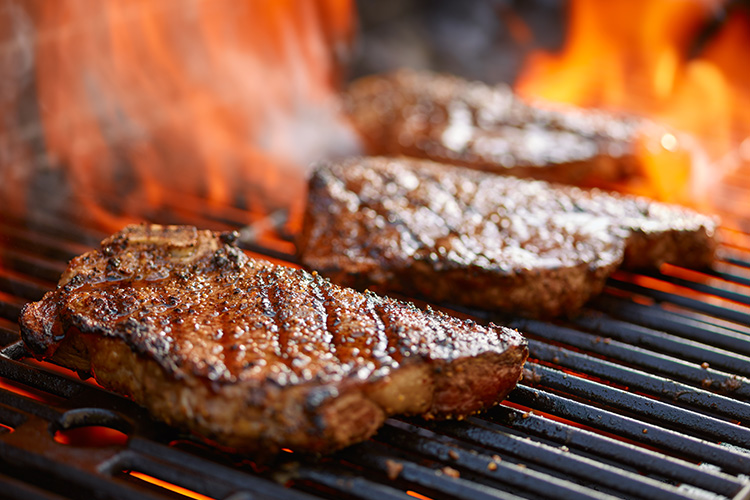 Steaks on a flame grill.